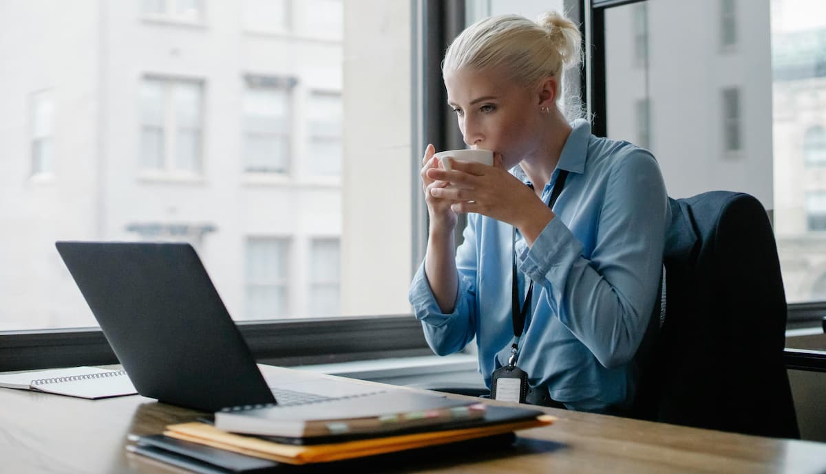Femme au bureau en train de boire un café tout en utilisant la solution oodrive work permettant la gestion et partage de données sensibles